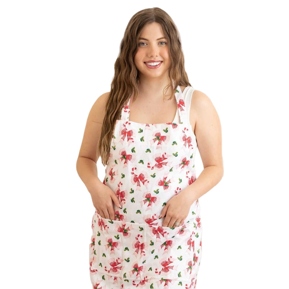 Woman wearing white Holly Jolly Bows Apron with red bows and holly leaf pattern