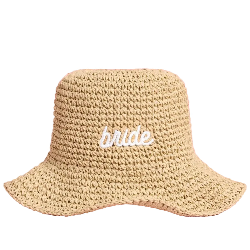 Beige straw bucket hat with 'bride' embroidered text on pink background