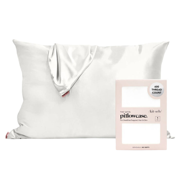 A white satin pillowcase draped over a white pillow, shown next to its light pink retail box labeled 'the pure pillowcase. kit-sch.
