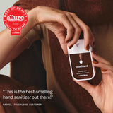 Person holding Touchland Power Mist hand sanitizer bottle in brown clothing