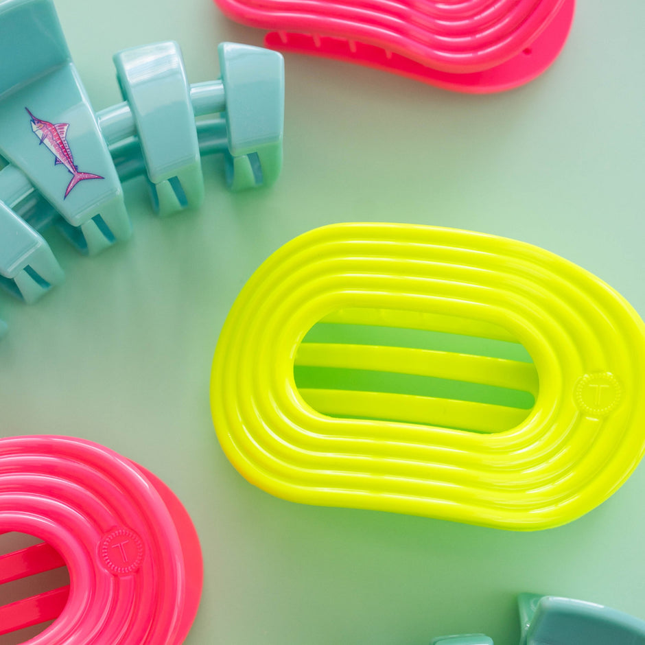 Colorful TELETIES hair clips in neon yellow, pink, and turquoise on mint green background