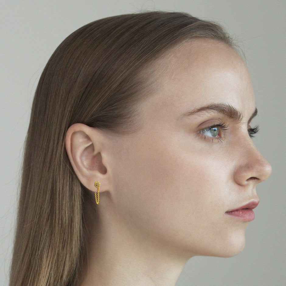 Gold CZ circle and chain stud earrings worn by woman in profile view