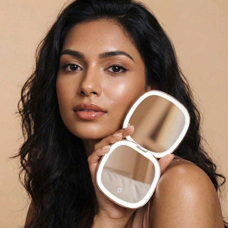 Woman holding FANCII Mila 2 LED compact mirror with illuminated display against neutral background