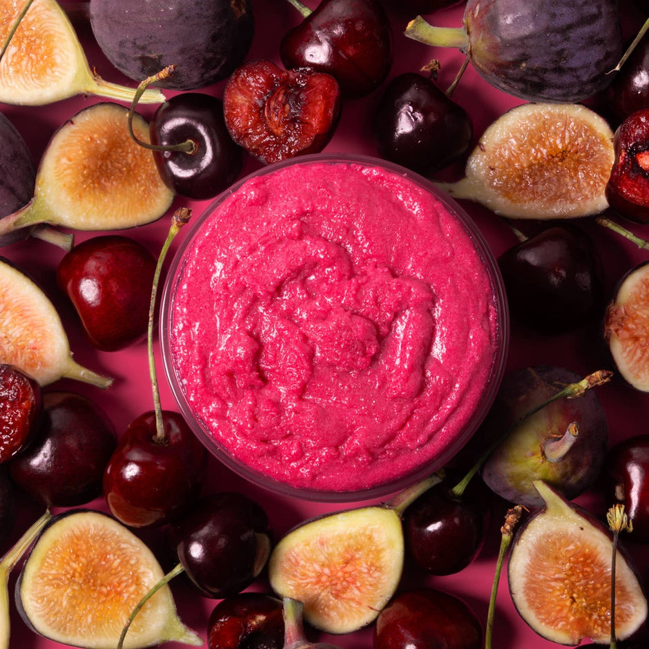 NCLA Beauty Fig & Cherry body scrub with fresh figs and cherries on pink background