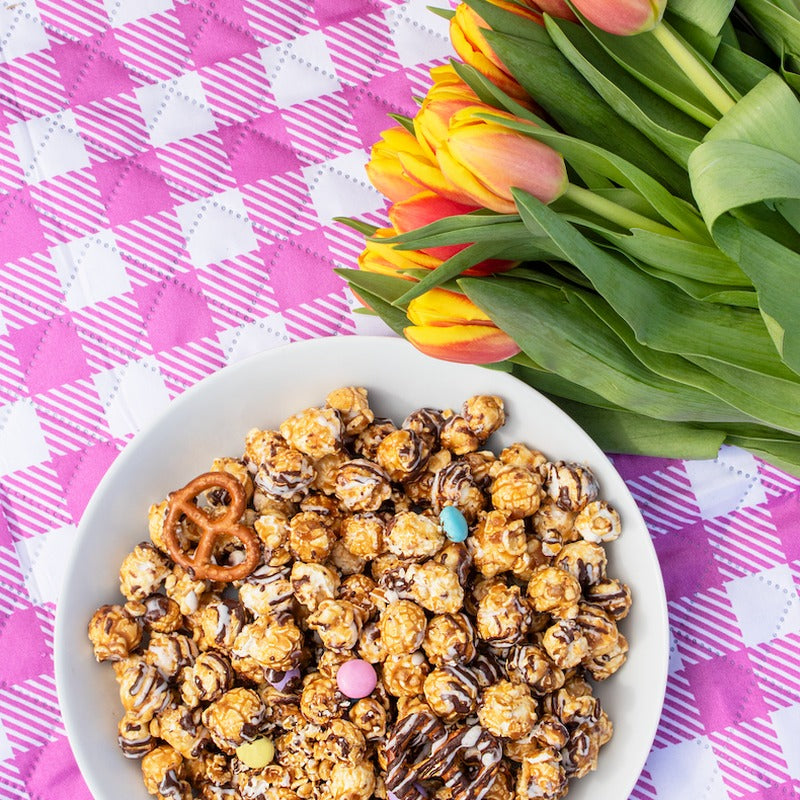 Spring Confetti Popcorn served on pink gingham tablecloth with yellow tulips and wicker basket