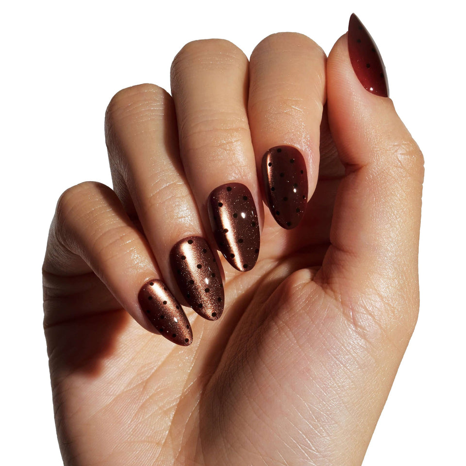 Deep burgundy glitter press-on nails with almond shape displayed on model's hand