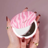 FANCII Mini Taylor compact mirror with light in blush zebra pattern held in hand with manicured nails
