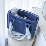 Navy blue tote organizer displayed on Prada box with white patterned handles and contents visible