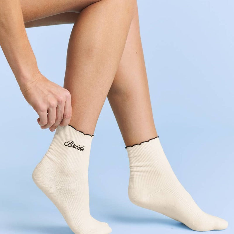 Bride ruffle socks worn on model's feet against blue background