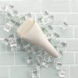 Ivory ice roller on mint green subway tile background surrounded by ice cubes