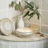 Decorative candle, soap, and plant on a shelf against a tiled wall.