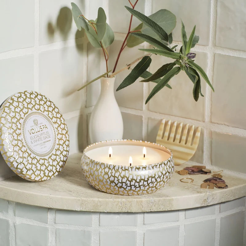 Decorative candle, soap, and plant on a shelf against a tiled wall.