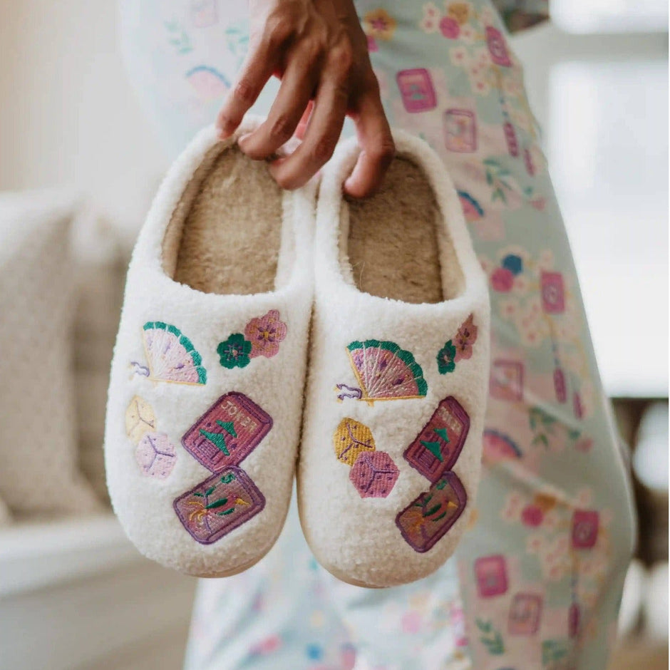 Woman holding cream Mahjong embroidered house slippers with colorful designs