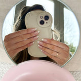 Person holding a phone with a unique case in front of a mirror