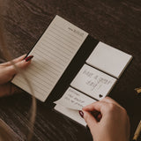 Hands holding open portable sticky notes booklet with date and to-do list reminders