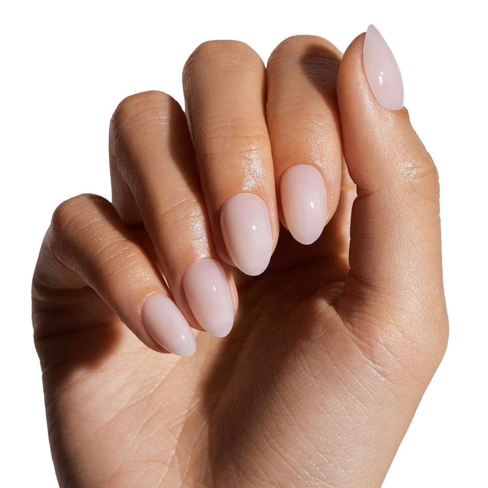 Coconut Milk almond press-on nails displayed on model's hand, showcasing glossy pale pink finish