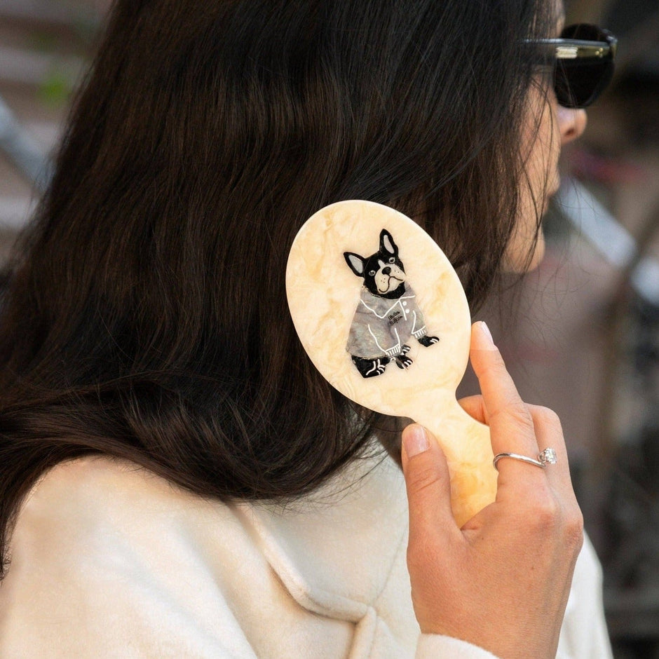 Hand-painted preppy puppy brush held by woman with dark hair, showing illustrated Boston Terrier design