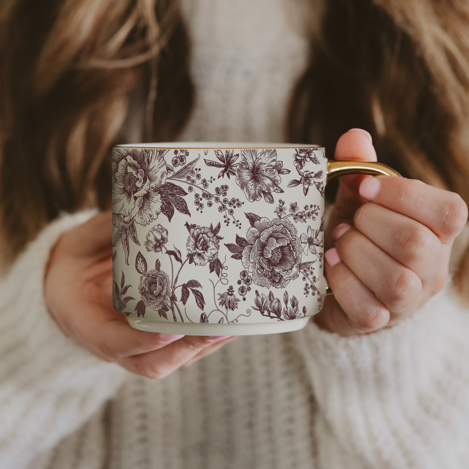 Woman holding brown delft floral coffee mug with vintage botanical pattern design