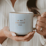 Woman holding white 'In My Engaged Era' coffee mug, displaying engagement ring