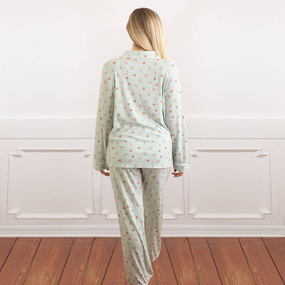 Woman wearing Candy Cane Cottage Luxe Long PJ Set in green striped pajamas, standing against white wall