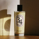 Diptyque 34 Boulevard Saint Germain Room Spray bottle on a wooden shelf in warm light