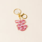 Pink floral sorority letter acrylic keychain with gold hardware on neutral background