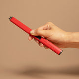Red rechargeable electric lighter held in hand against neutral background