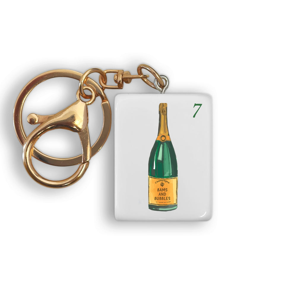 Gold mahjong tile keychain with champagne bottle design and brass clasp attachment