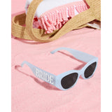 Blue bride sunglasses styled with pink beach towel and straw bag for bachelorette party
