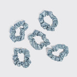 Five haze blue satin sleep scrunchies arranged on white background