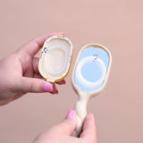 TELETIES Mini Detangler Brush for Medium Hair in Tan, held in hands against pink background