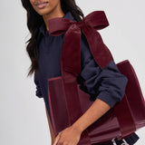 Woman holding red velvet bow jelly tote bag with navy blue sweater