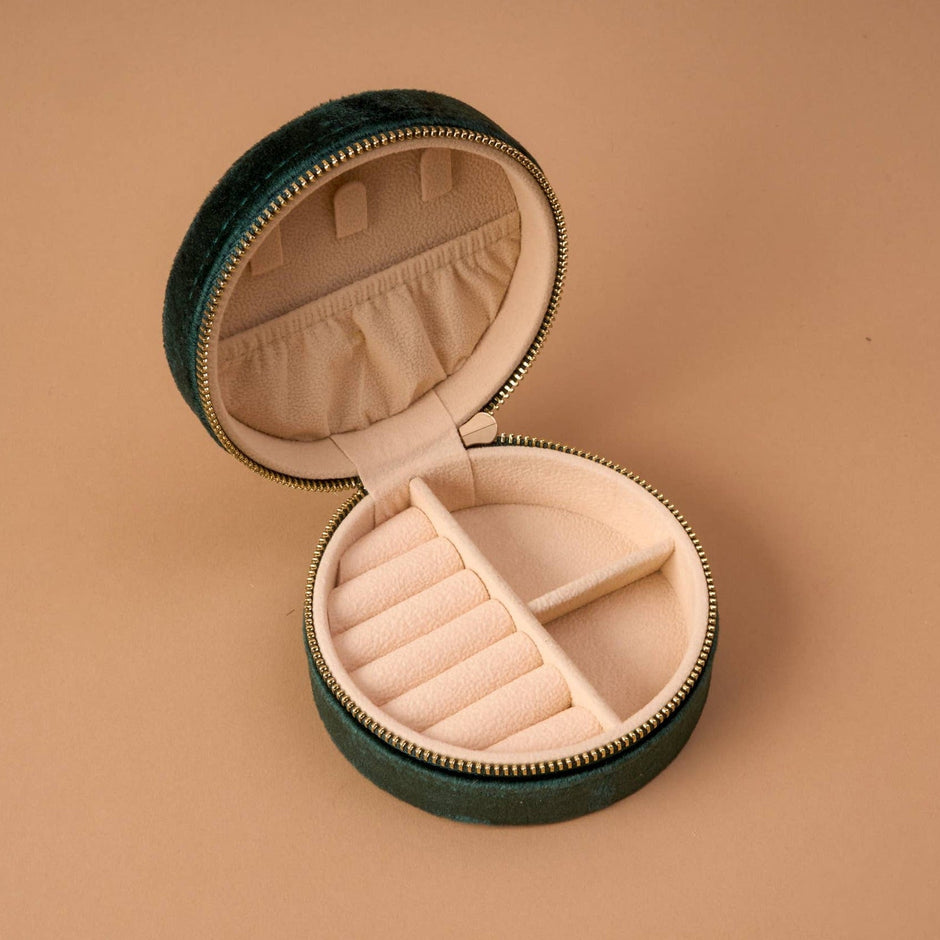Round velvet jewelry case in teddy bear color, open to show pink interior compartments and storage