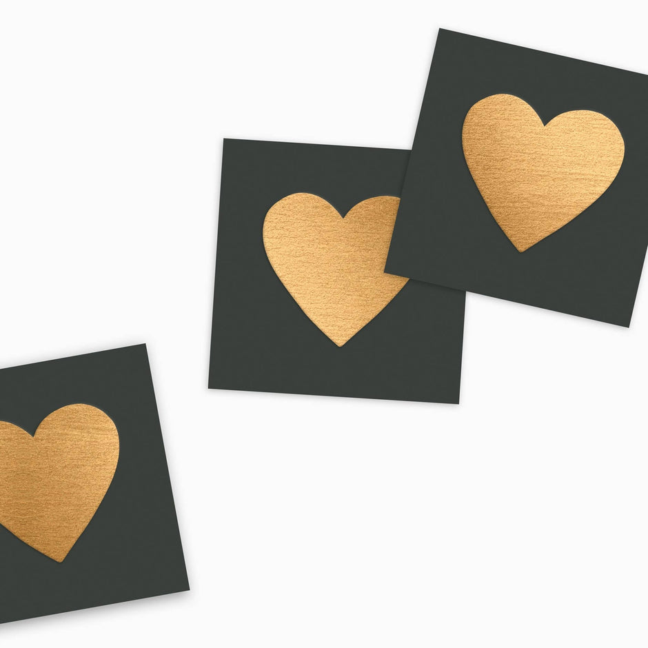 Three dark matchboxes with embossed gold heart designs displayed on white background