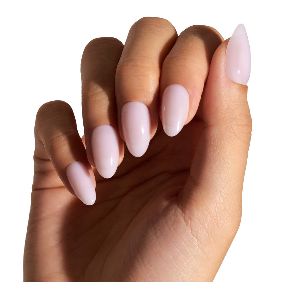 Pink ballerina almond press-on nails worn on hand against white background