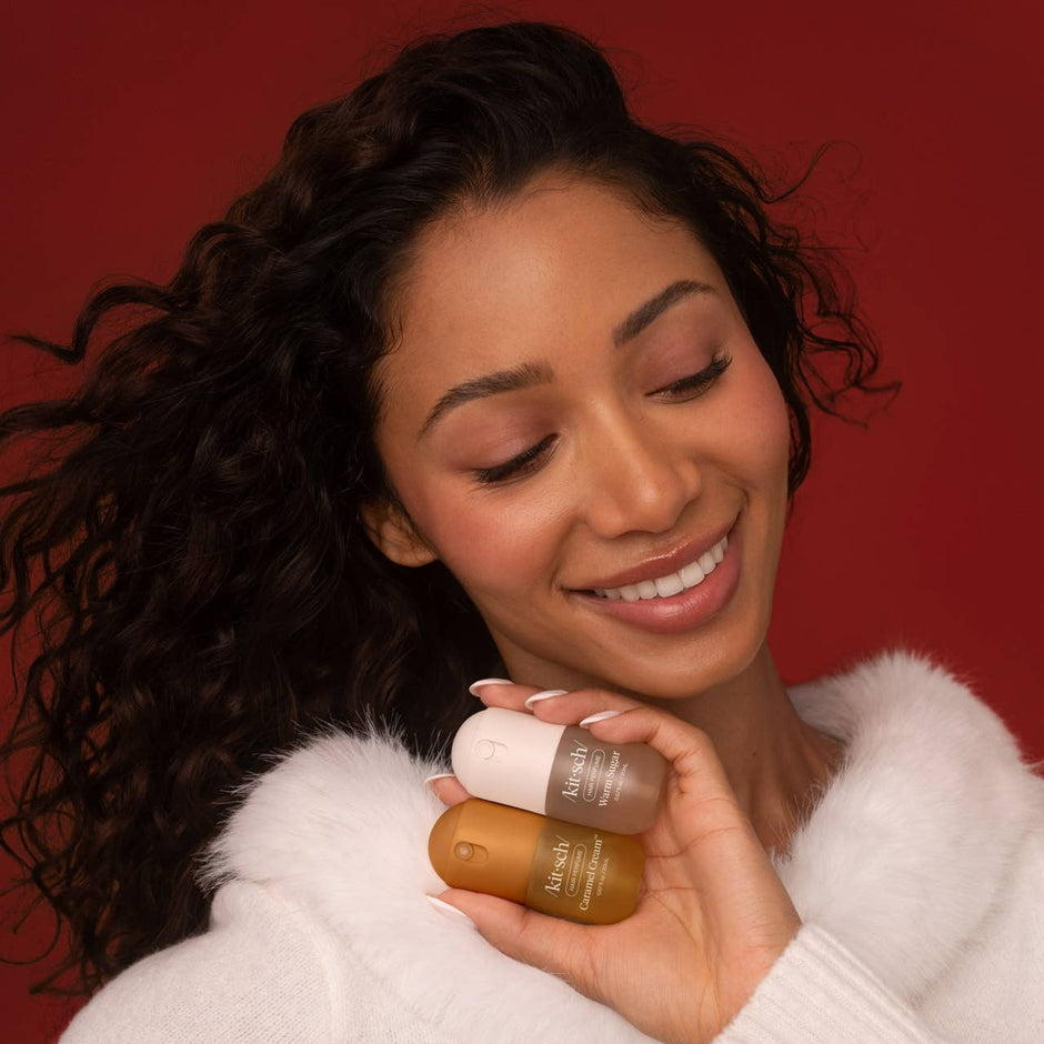 Woman holding two hair care bottles against red background, smiling
