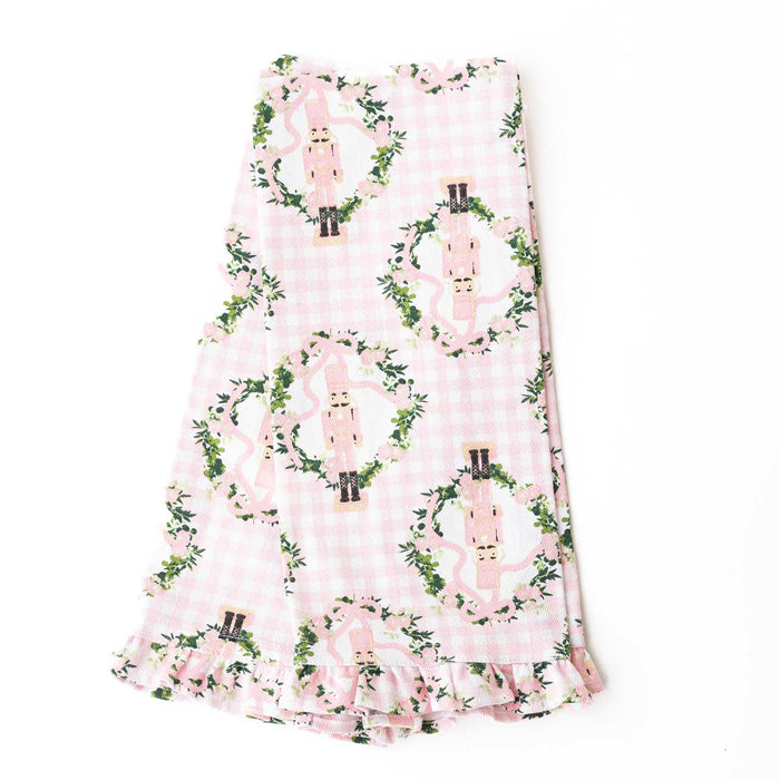 Pink gingham kitchen towel with nutcracker and ivy vine pattern, featuring ruffled edge