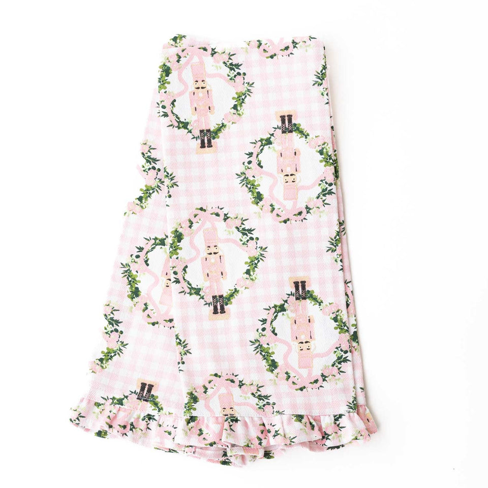 Pink gingham kitchen towel with nutcracker and ivy vine pattern, featuring ruffled edge