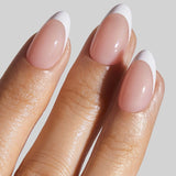 French manicure almond nails with white tips and pink base on model's hand against neutral background