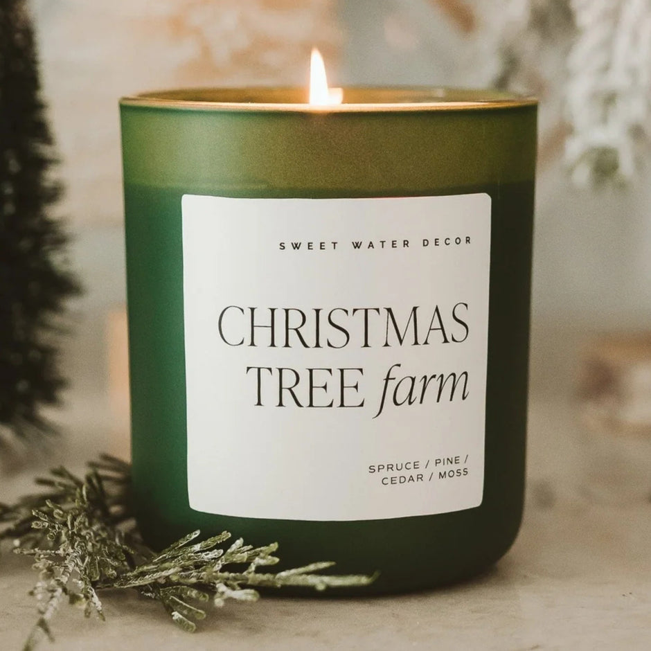 Christmas Tree Farm soy candle by Sweet Water Decor in green glass with lit flame and evergreen styling