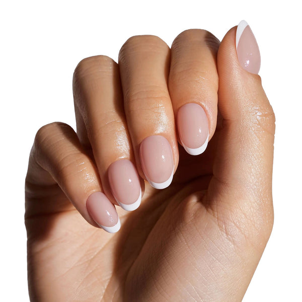 Woman wearing classic French manicure press-on nails with white tips on short round shape