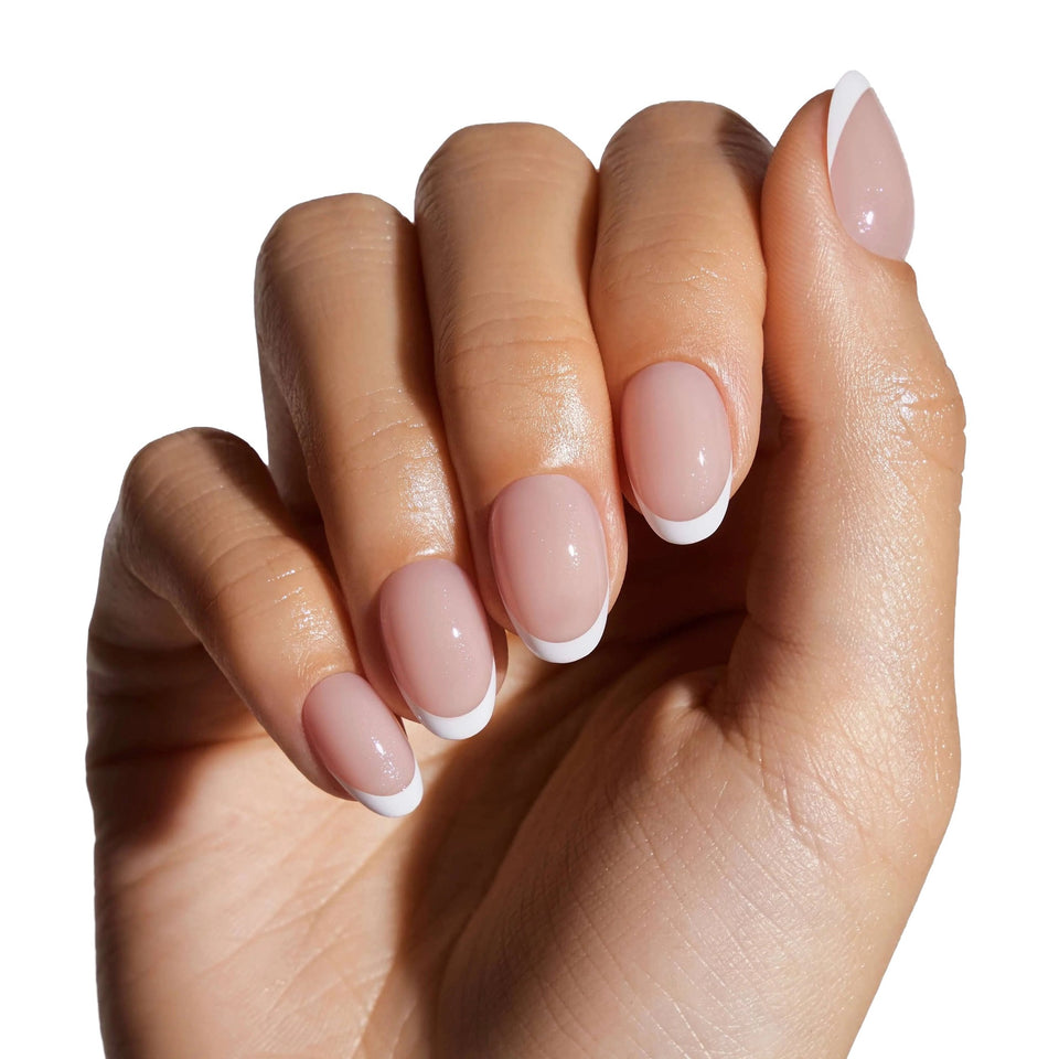 Woman wearing classic French manicure press-on nails with white tips on short round shape