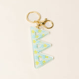 Light blue acrylic letter keychain with yellow floral pattern and gold hardware
