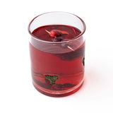 Holly Icon Beaded Drinking Glass filled with red beverage and berries on stick