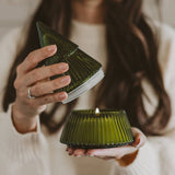 Woman holding Fraser Fir soy candle in green glass tree jar with lid, styled home decor