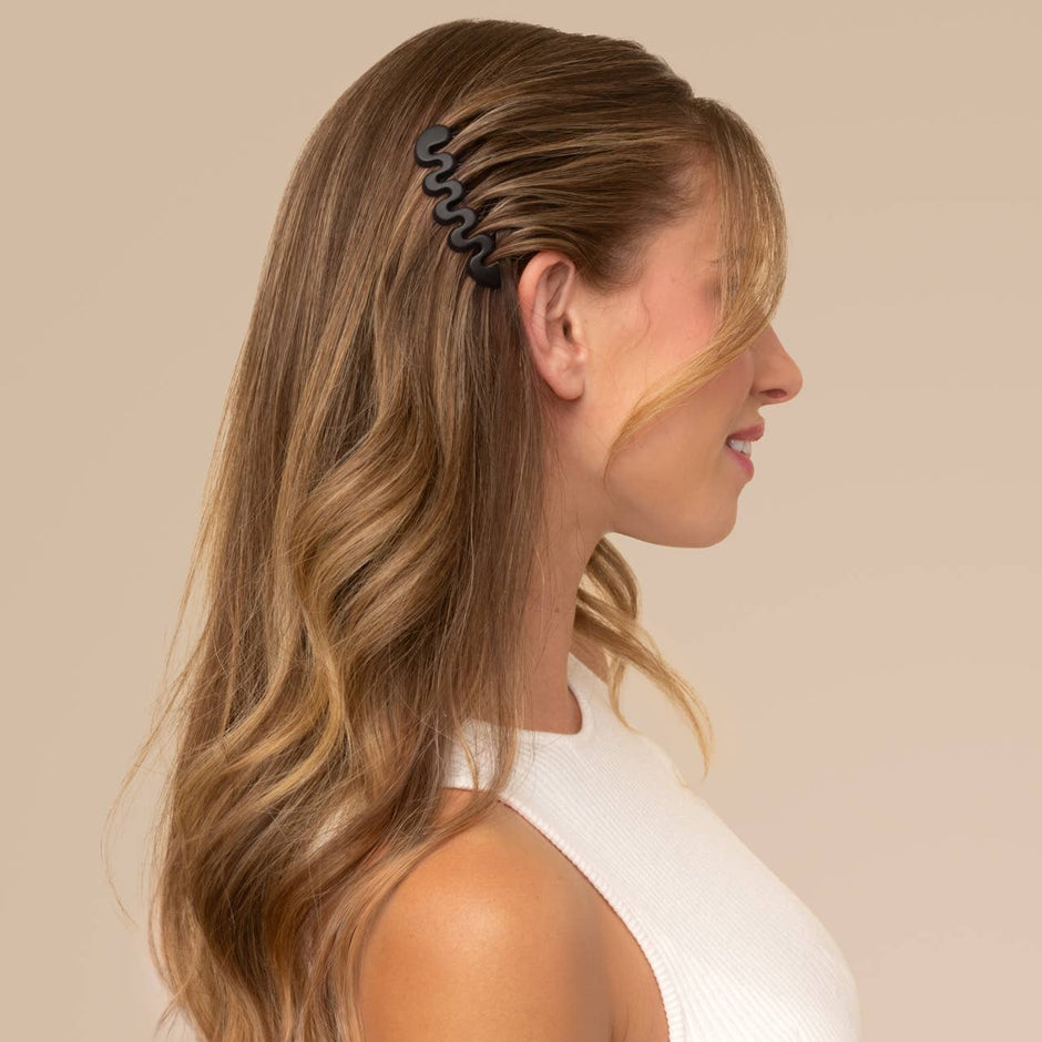 Black French hair combs holding back long wavy brown hair on a model wearing white.