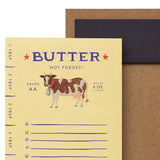 Butter notepad with a cow illustration and measurement scale, housed in a brown cardboard sleeve.