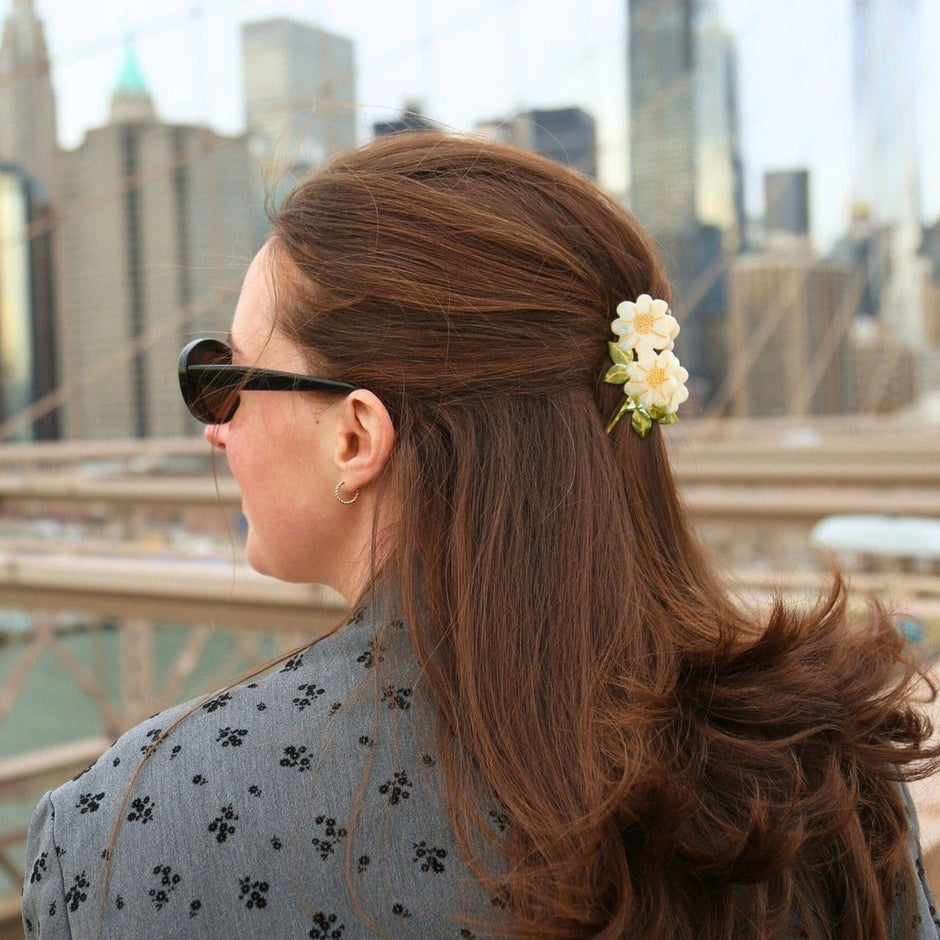Hand-painted vintage daisy stem claw hair clip worn in brown hair against NYC skyline backdrop
