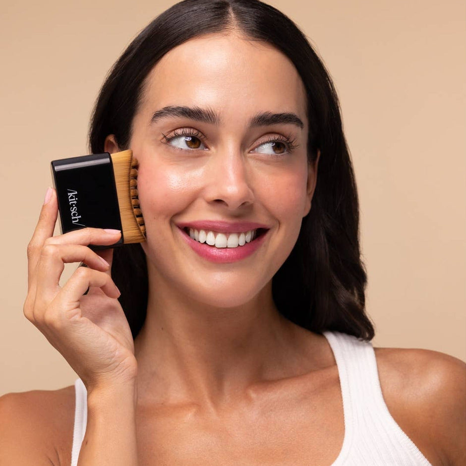 Woman holding Kitsch black lymphatic contour face brush against neutral beige background