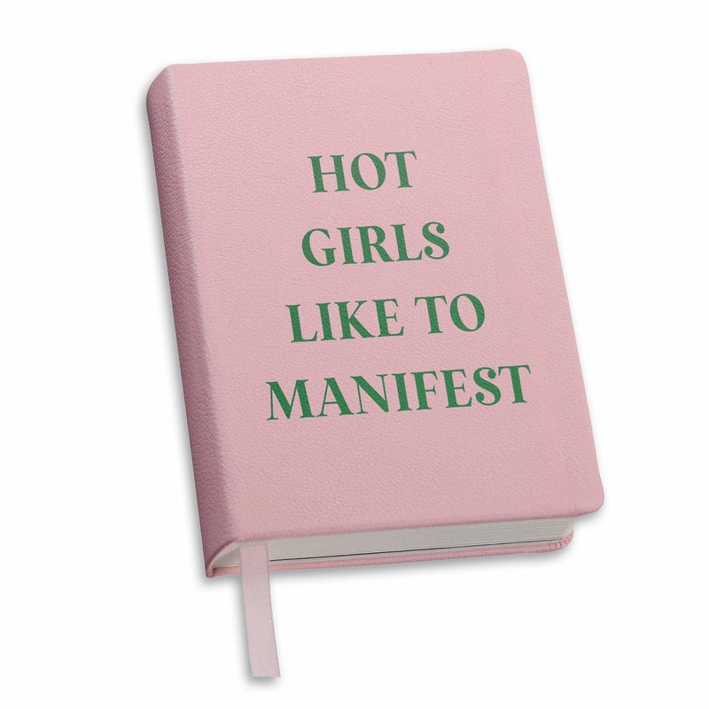 Pink hardcover journal with green text reading 'Hot Girls Like to Manifest' and ribbon bookmark
